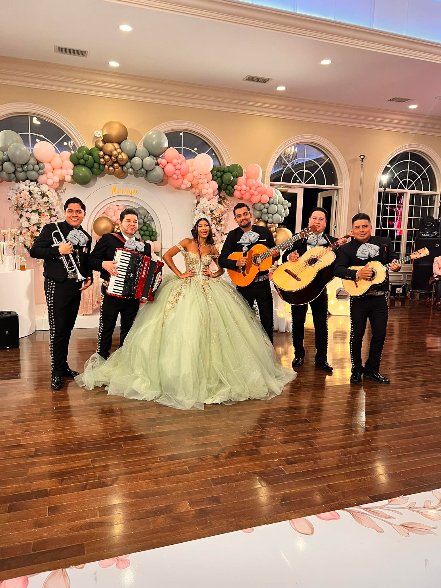 Mariachi with a guest of honor at a party with balloons and flowers.